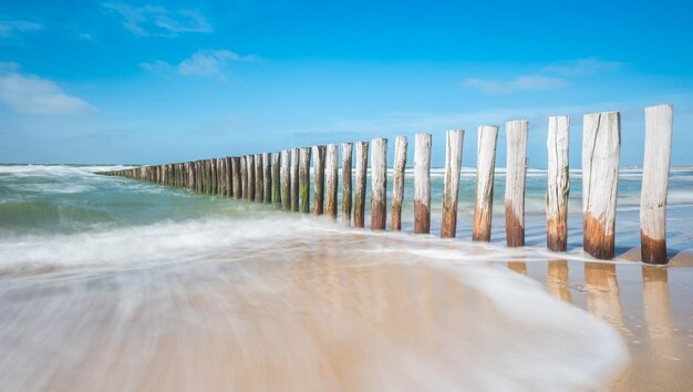 Wellenbrecher aus Holzpfählen am Strand