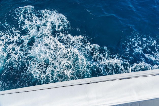 Wellenspur mit weißem Schaum auf einer Wasseroberfläche hinter einer sich schnell bewegenden Yacht