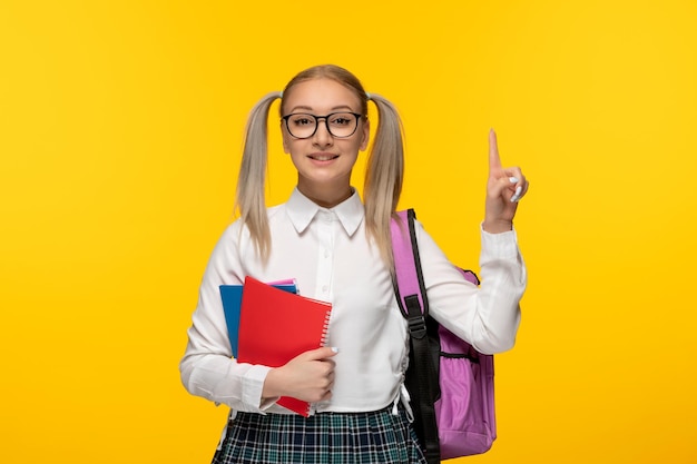 Welttag des Buches aufgeregtes Schulmädchen, das mit dem Finger nach oben zeigt und bunte Notizbücher hält