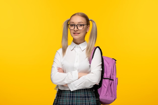 Welttag des Buches glückliches blondes Mädchen mit gekreuzten Händen rosa Rucksack auf gelbem Hintergrund