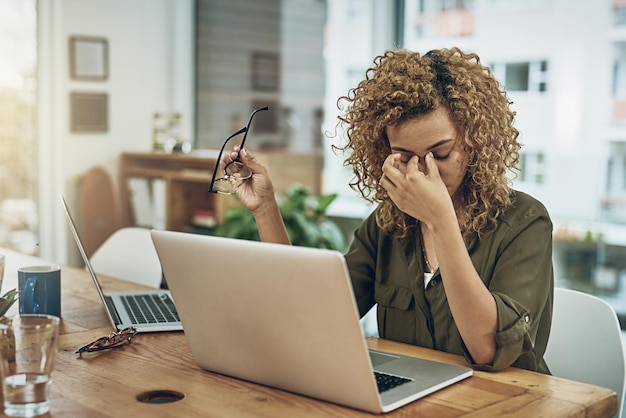 Wenn der Weg zum Erfolg in Stress führt. Aufnahme einer jungen Frau, die unter Stress leidet, während sie einen Computer an ihrem Schreibtisch benutzt.