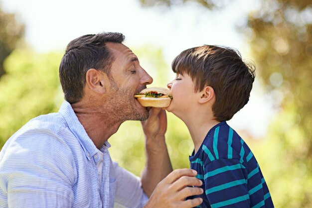 Wer hat den größten Biss Aufnahme eines Vaters und eines Sohnes, die gleichzeitig in ein Sandwich beißen