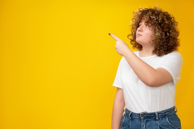 Werbehintergrund Falsche Ernährung Ungesunde Ernährung Fettleibigkeitssymptome Zweifelhafte übergewichtige junge Frau mit lockigem Haar, die etwas auf orangefarbenem Kopierraum präsentiert