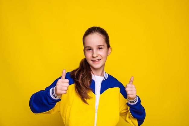 Werbung für Sportbekleidung von guter Qualität, Mädchen in Sportbekleidung in den Farben der ukrainischen Flagge an der gelben Wand