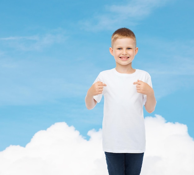 Werbung, Gesten, Menschen und Kindheitskonzept - lächelnder kleiner Junge im weißen T-Shirt, der mit dem Finger auf sich selbst über Himmelshintergrund zeigt