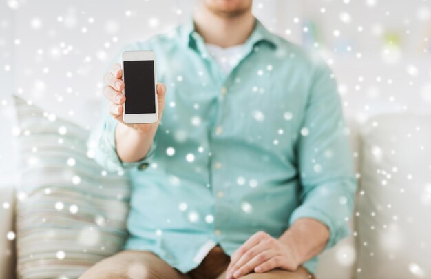 Werbung, Menschen, Zuhause und Technologiekonzept - Nahaufnahme eines Mannes, der den leeren Smartphone-Bildschirm zeigt, der zu Hause auf der Couch sitzt