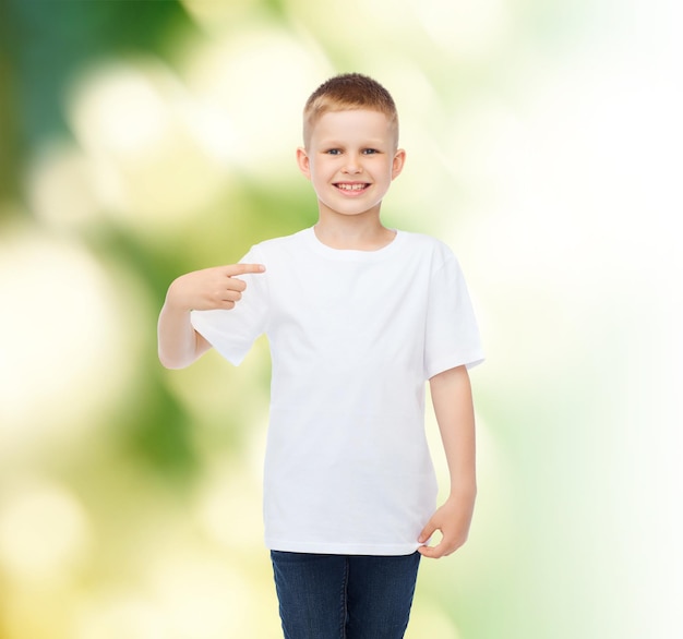 werbung, ökologie, gestik und kindheitskonzept - lächelnder junge im weißen leeren t-shirt, das mit dem finger auf sich selbst über grünem hintergrund zeigt