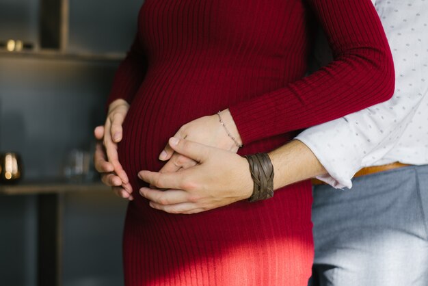 Werdende Eltern Ehemann und Ehefrau halten ihre Hände auf schwangeren Bauch, während sie auf ihr Baby warten