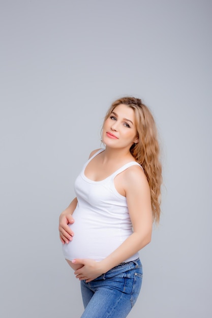 Werdende Mutter berührt ihren Bauch auf einem weißen Hintergrund Studioaufnahme