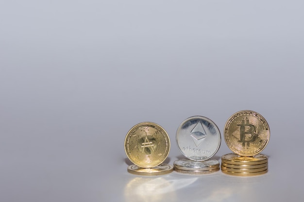 Wertvolle Kryptomünzen bitcoin ether und ada in einer Reihe mit grauem Hintergrund, rechte Ansicht