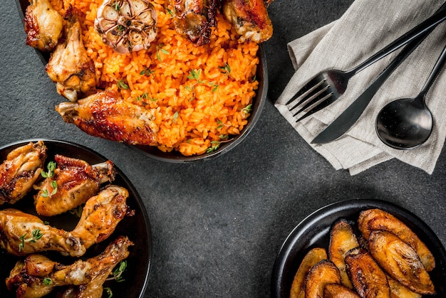 Westafrikanische nationale Küche. Jollofreis mit gegrillten Hähnchenflügeln und gebratenen Bananenbananen