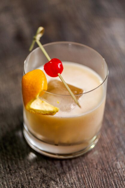 Whiskey-Sauer-Cocktail garniert mit Orange und Kirsche.