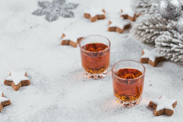 Whisky, brandy o licor, galletas y decoraciones de vacaciones de invierno sobre fondo blanco. Concepto de vacaciones de temporada.