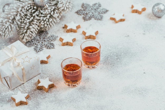 Whisky, Brandy oder Schnaps, Kekse und Winterurlaubsdekorationen auf weißem Hintergrund. Saisonale Feiertage Konzept.