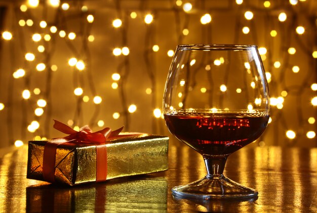 Whisky, coñac, brandy y caja de regalo en mesa de madera. Composición de celebración en la luz