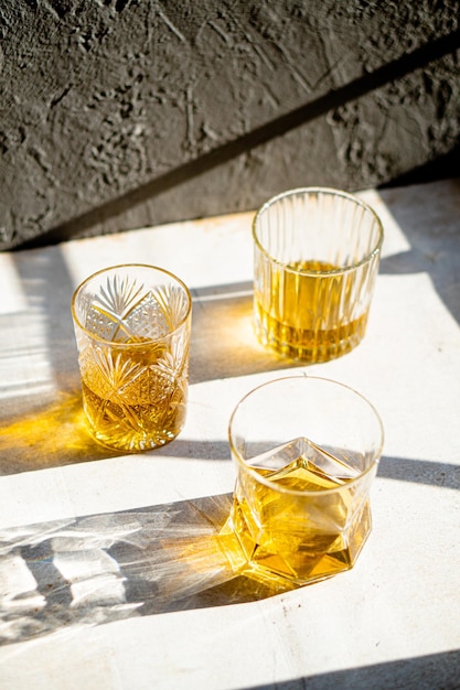 Whisky en copas en la mesa en la brillante bebida amarilla de la luz del sol