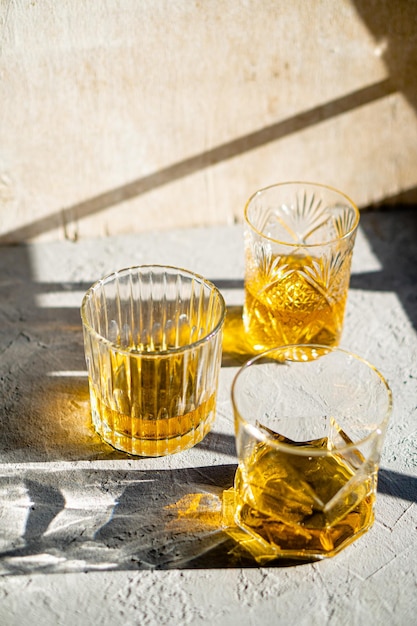 Whisky en copas en la mesa en la brillante bebida amarilla de la luz del sol