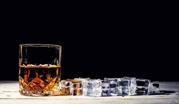 Whisky con cubitos de hielo sobre fondo de madera