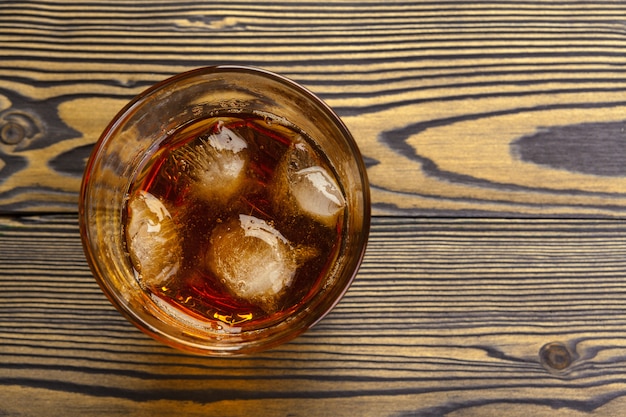 Whisky con cubitos de hielo sobre superficie de madera