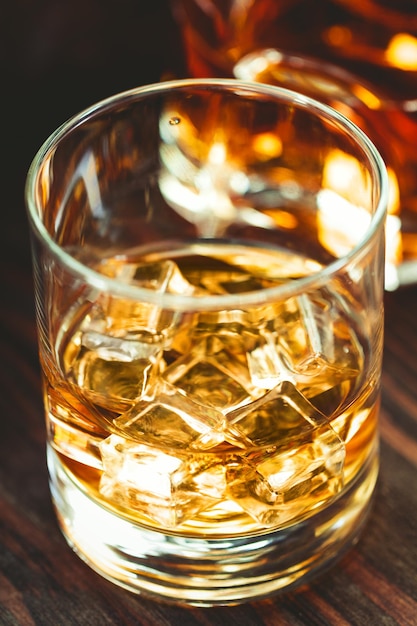 Whisky con cubitos de hielo en un vaso sobre una mesa de madera