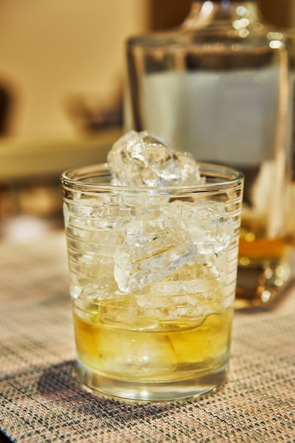 Whisky exclusivo en vaso con hielo en el fondo de la botella