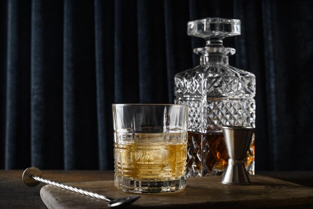 Whisky frío servido en rocas sobre fondo de moda cortina azul oscuro