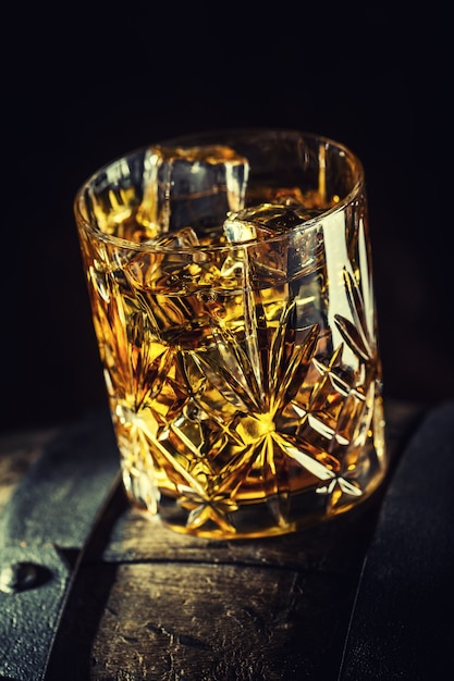 Whisky-Getränk. Glas Whisky auf altem Holzfass.