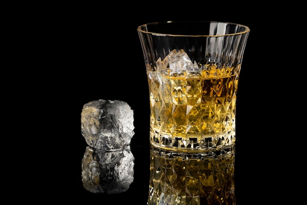 Whisky y hielo con reflejo en un fondo negro