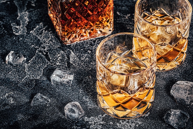 Whisky con hielo sobre un fondo oscuro de piedra.