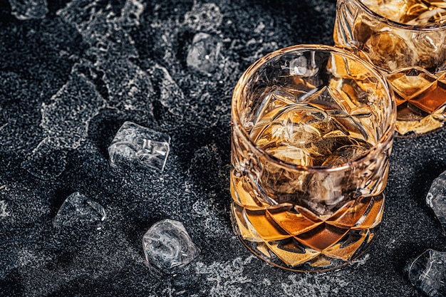 Whisky con hielo sobre un fondo oscuro de piedra.