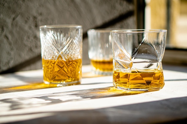 Whisky in Gläsern auf dem Tisch in hellem Sonnenlicht gelbes Getränk