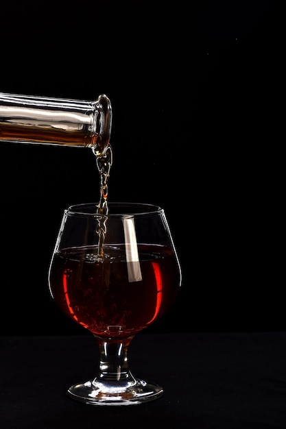 Whisky in niedriges Glas auf schwarzem Hintergrund gegossen