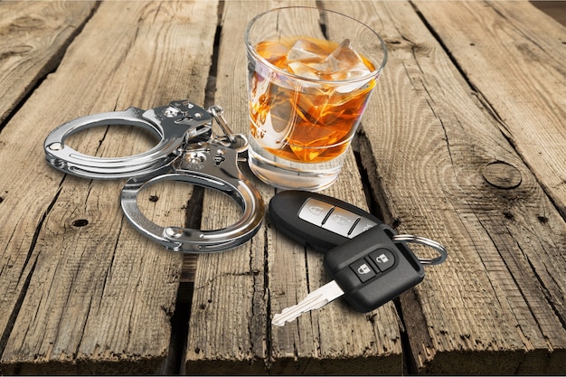 Whisky con llaves del coche y concepto de esposas para beber y conducir