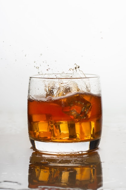 Whisky mit Eis in einem Glas mit Spritzern