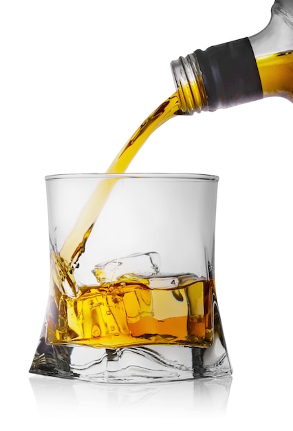 Whisky que vierte de una botella en un vaso con hielo