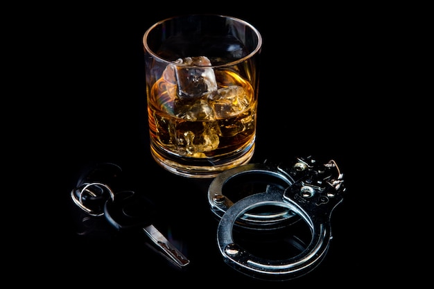 Whisky en las rocas con esposas y llave del coche