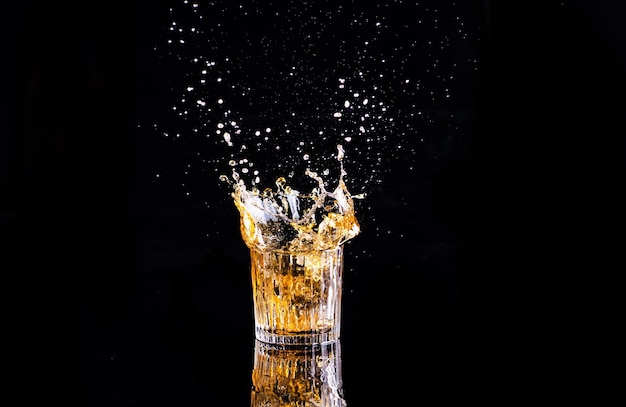 Foto whisky con salpicaduras de brandy de fondo negro en un vaso