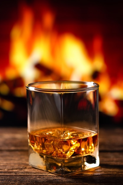 Whisky en un vaso con chimenea borrosa