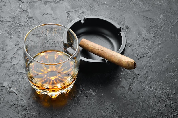 Whisky en vasos y cigarros cubanos en una mesa de piedra negra Vista superior Espacio libre para su texto