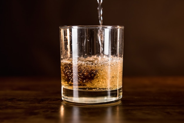 Whiskygetränk, das herein in das Glas auf hölzerner Gegenstange gegossen wird