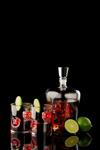 Whiskygläser mit Rum oder Whisky mit roten Würfeln und Karaffe mit Schädel auf dunklem Glashintergrund