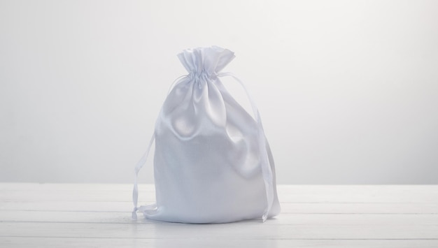 Foto white gift bag made with silk material on white background stylish soft pouch with present inside