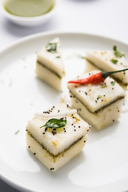 White Sandwich Dhokla es un bocadillo salado indio hecho de harina de garbanzo o harina de arroz, originado en Gujarat. Servido con chutney verde y tamarindo. enfoque selectivo