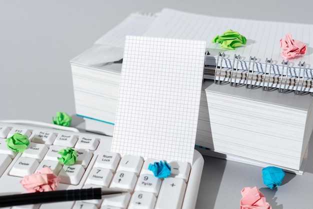 Wichtige Nachricht, die auf einem Blatt Papier auf dem Schreibtisch mit Tastatur, Büchern, Notizbüchern und Stift präsentiert wird