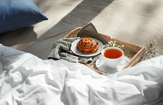 Wicker tablett mit leckerem frühstück auf dem bett