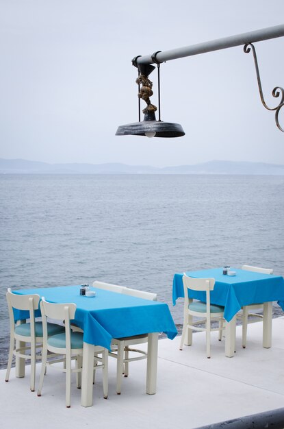Wicker Tische und Stühle auf der Terrasse eines gemütlichen Sommercafés mit Meerblick