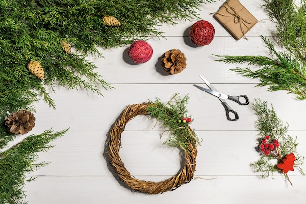 Wie man einen Weihnachtstürkranz macht. Der Arbeitsprozess. Der Arbeitsplatz des Dekorateurs. Ansicht von oben. Platz kopieren. Stillleben. Flach liegen.