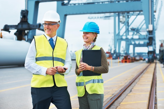 Wie Sie mit Ihren Arbeitskollegen auskommen. Zwei Hafenarbeiter stehen zusammen und lächeln bei der Arbeit.