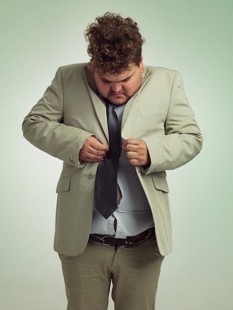 Wie wird das gemacht Aufnahme eines übergewichtigen Mannes im Anzug, der versucht, seine Jacke zuzuknöpfen