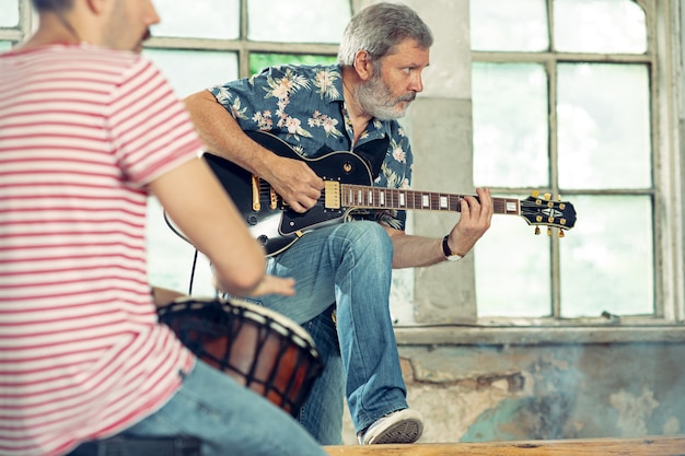 Wiederholung der Rockmusikband. Bassgitarrist, E-Gitarrist und Schlagzeuger im Loft. Rockmusik- und Jam-Session-Konzept. Leidenschaft für Musik- und Jugendkulturkonzepte